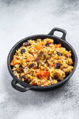 Tavada kuzu eti ve sebzeli pilav. Beyaz ahşap arka plan. Üst görünüm.