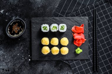 Suşi, salatalık, somon ve karides ile taş tepside yuvarlanıyor. Siyah arka plan. Üst görünüm.