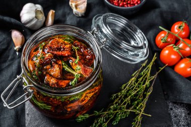 Zeytinyağında kurutulmuş domates, baharat ve bitki tarifi. Siyah arka plan. Üst görünüm.