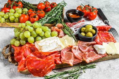 Üzümlü soğuk et, prosciutto, jambon, kurutulmuş et, sucuklu salam, fuet, camembert ve keçi peyniri. Gri arka plan. Üst görünüm.