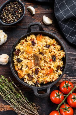 Tavada kuzu eti ve sebzeli pilav. Koyu ahşap arka plan. Üst görünüm.