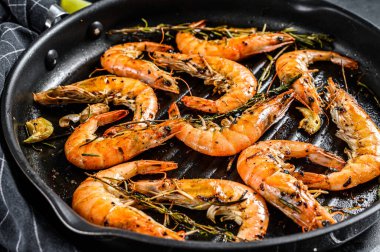 Izgara dev karides, sarımsaklı karides, limon, tavada baharat. Siyah arka plan. Üst görünüm.
