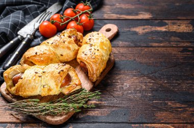 Hamurda sosisli sandviç dilimleri var. Koyu ahşap arka plan. Üst Manzara. Boşluğu kopyala.