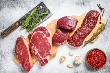 Variety of raw black angus beef meat steaks fillet Mignon, rib eye or cowboy, Striploin or new york, skirt or machete. White background. Top view. clipart