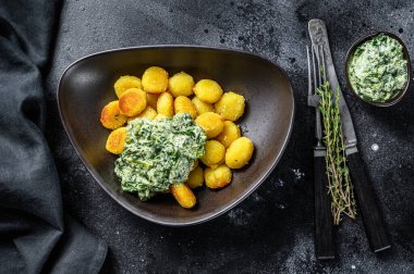 Kızarmış gnocchi patates makarna ve ıspanak. Siyah arka plan. Üst görünüm.