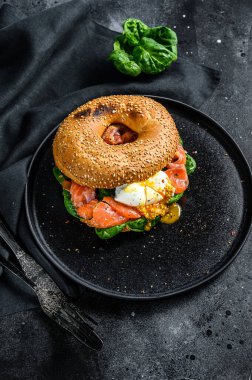 Yumuşak peynirli, ıspanaklı ve yumurtalı somon tostu. Siyah arka plan. Üst görünüm.