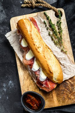 Jamon jambonlu sandviç, paleta iberica, kesim tahtasında Camembert peyniri. Siyah arkaplan, üst görünüm