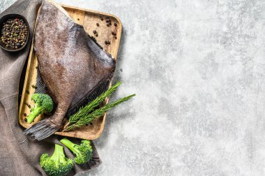 Biberiye ve brokoliyle ahşap tepside çiğ taze John Dory balığı. Gri arka plan. Üst Manzara. Boşluğu kopyala.