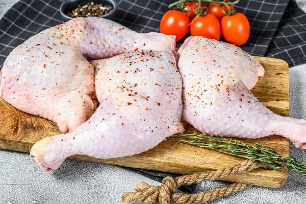 Fresh raw chicken thighs, legs on a cutting Board with spices, cooking. Gray background. Top view. Copy space.