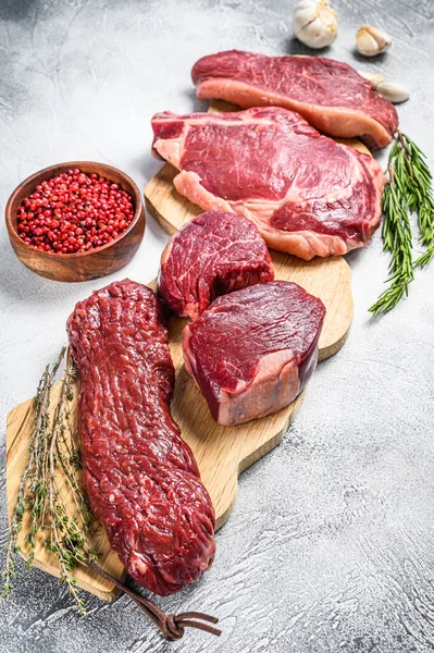 Variety of raw black angus beef meat steaks fillet Mignon, rib eye or cowboy, Striploin or new york, skirt or machete. White background. Top view.