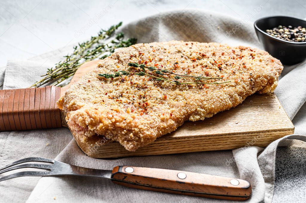 Raw chicken schnitzel in breadcrumbs. Gray background. Top view.