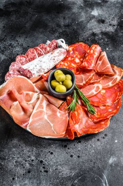 Geleneksel İspanyol mezelerinden yapılmış bir tabak et. Chorizo, Jamon Serrano, Lomo ve Fuet. Siyah arka plan. Üst görünüm.