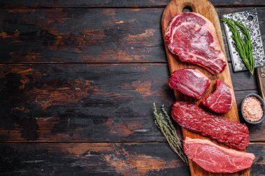 Çiğ siyah angus bifteği fileto Mignon, pirzola ya da kovboy, Striploin ya da New York, etek ya da pala. Ahşap arka plan. Üst Manzara. Boşluğu kopyala.
