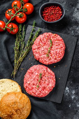 Hamburger pişirmek için gerekli malzemeler. Kıymalı börek, çörek, domates, otlar ve baharatlar. Siyah arka plan. Üst görünüm.