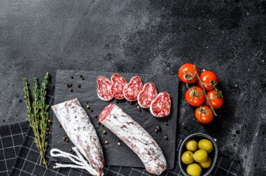 Fuet Salam dilimleri ve Rosemary. Geleneksel İspanyol sosisi. Siyah arka plan. Üst Manzara. Metin için boşluk.