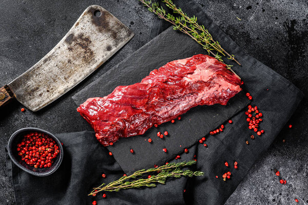 Raw strip vegas beef steak with pink pepper and thyme. Black background. Top view.