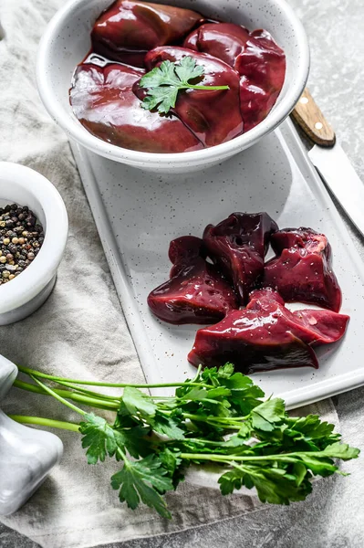 Bir kasede çiğ tavuk ciğeri. Gri arka plan. Üst görünüm