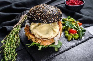 Siyah ekmekli ev yapımı hamburger, çırpılmış yumurta ve roka. Kara burger. Siyah arka plan. Üst görünüm.