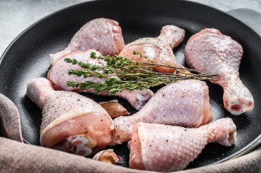 Tavada baharat olan çiğ tavuk budu. Beyaz arka plan. Üst görünüm.