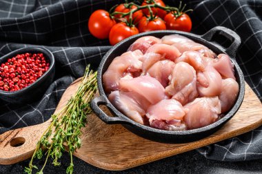 Tavada derisi olmayan dilimlenmiş tavuk butları. Siyah arka plan. Üst görünüm.