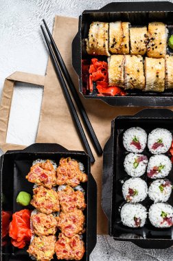 Suşi teslimat paketinde yuvarlanıyor, suşi siparişi veriliyor. Gri arka plan. Üst görünüm.