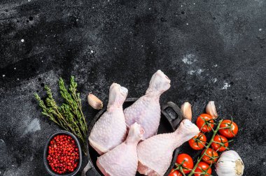Taze tavuk budu, kızartma tavasında pişirmek için malzemeli bacaklar. Organik kümes hayvanları. Siyah arka plan. Üst görünüm.