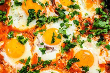 Ev yapımı shakshuka, kızarmış yumurta, soğan, dolmalık biber, domates ve tavada maydanoz. Gri arka plan. Üst görünüm.