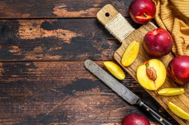 Kesme tahtasında dilimlenmiş kırmızı nektarinler. Karanlık ahşap arka plan. Üst Manzara. Boşluğu kopyala.