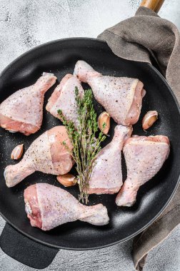 Çiğ organik tavuk budu, baharat ve tavada pişirmeye hazır sarımsak. Beyaz arka plan. Üst görünüm.