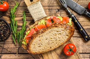 Avokado ve somonlu sağlıklı sandviç. Ahşap arka plan. Üst görünüm.