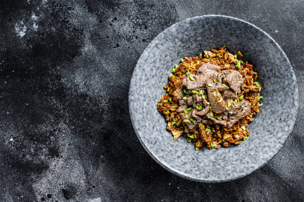 Chinese wok fried rice with vegetables and beef. Black background. Top view. Copy space.