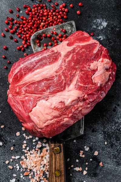 Raw Chuck eye roll steak on meat cleaver. Organic beef. Black background. Top view.