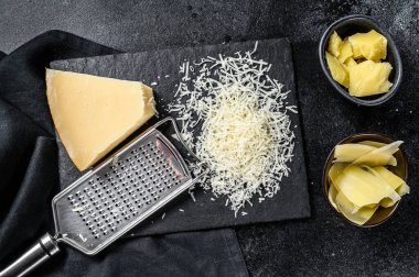 İtalyan sert parmesan peyniri dilimi, kesilmiş, rendelenmiş. Siyah arka plan. Üst görünüm.