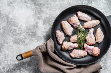 Tavada baharat ve otlarla marine edilmiş tavuk kanatları. Gri arka plan. Üst Manzara. Boşluğu kopyala.