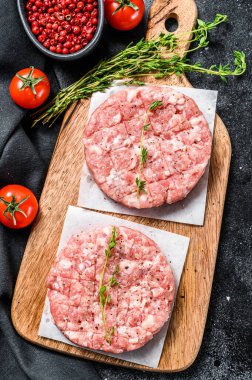 Çiğ tavuk köftesi, kıyma tahtasında kıymalı pirzola. Organik kıyma. Siyah arka plan. Üst görünüm.