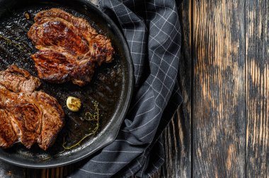 Chuck 'ın tavada pişirdiği ızgara mermer biftek. Karanlık arka plan. Üst Manzara. Boşluğu kopyala.