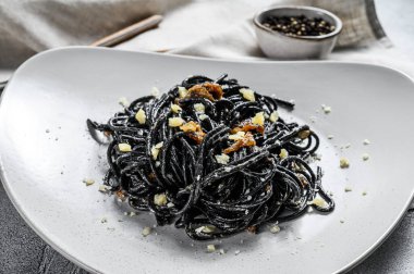 Krema soslu ton balıklı siyah spagetti makarna. Gri arka plan. Üst görünüm.