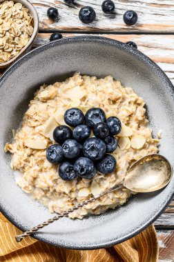 Yabanmersinli ve bademli yulaf lapası. Beyaz ahşap arka plan. Üst görünüm.