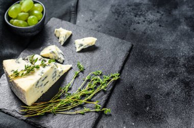 Kesme tahtasındaki üzümlü mavi peynirin üçgeni. Siyah arka plan. Üst Manzara. Boşluğu kopyala.