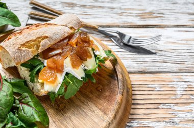 Keçi peynirli sandviç, armut reçeli, pazı ve baget ekmekli ıspanak. Beyaz ahşap arka plan. Üst Manzara. Boşluğu kopyala.