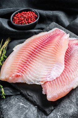 Taze tilapia filetosu ve kekik. Siyah arka plan. Üst görünüm.