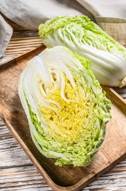 Çin lahanası kesiyorum. Organik sebzeler. Beyaz ahşap arka plan. Üst görünüm.