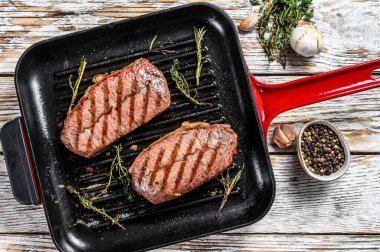 Kızartma tavasında ızgara et üst bıçaklı biftekler. Gri arka plan. Üst görünüm.