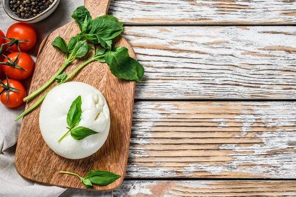 Italian Burrata buffalo cheese with Basil leaves. White wooden background. Top view. Copy space.