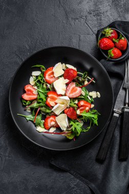 Camembert, çilek, fındık, pazı ve roka ile sağlıklı ve lezzetli bir salata. Siyah arka plan. Üst görünüm.