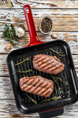 Kızartma tavasında ızgara et üst bıçaklı biftekler. Gri arka plan. Üst görünüm.