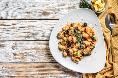 Conchiglie domatesli İtalyan makarnası, zeytin, kapari, ançüez. Beyaz arka plan. Üst Manzara. Boşluğu kopyala.