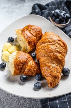 Fransız tereyağlı kruvasan ve yaban mersini tabağı. Gri arka plan. Üst görünüm.