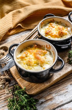 Julienne, ahşap bir masada porsiyon şeklinde tavuk ve peynirle. Beyaz arka plan. Üst görünüm.