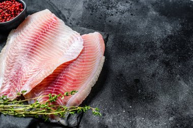 Taze tilapia filetosu ve kekik. Siyah arka plan. Üst Manzara. Boşluğu kopyala.